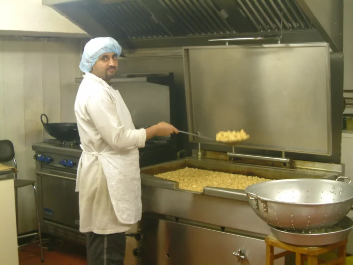 A male factory worker frying namak para at an old Tayyabah Factory